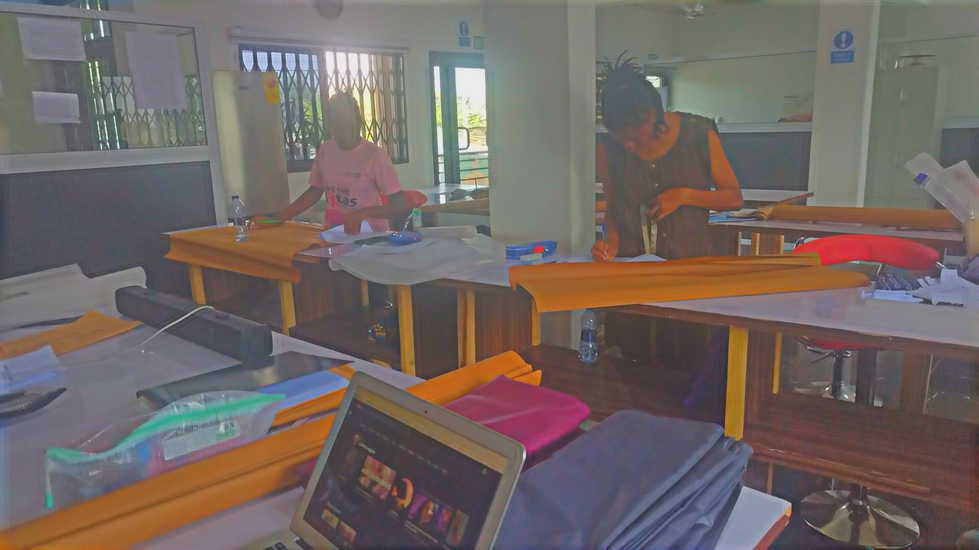 A picture of 2 participants working on their fashion designing projects at the workshop in Ghana